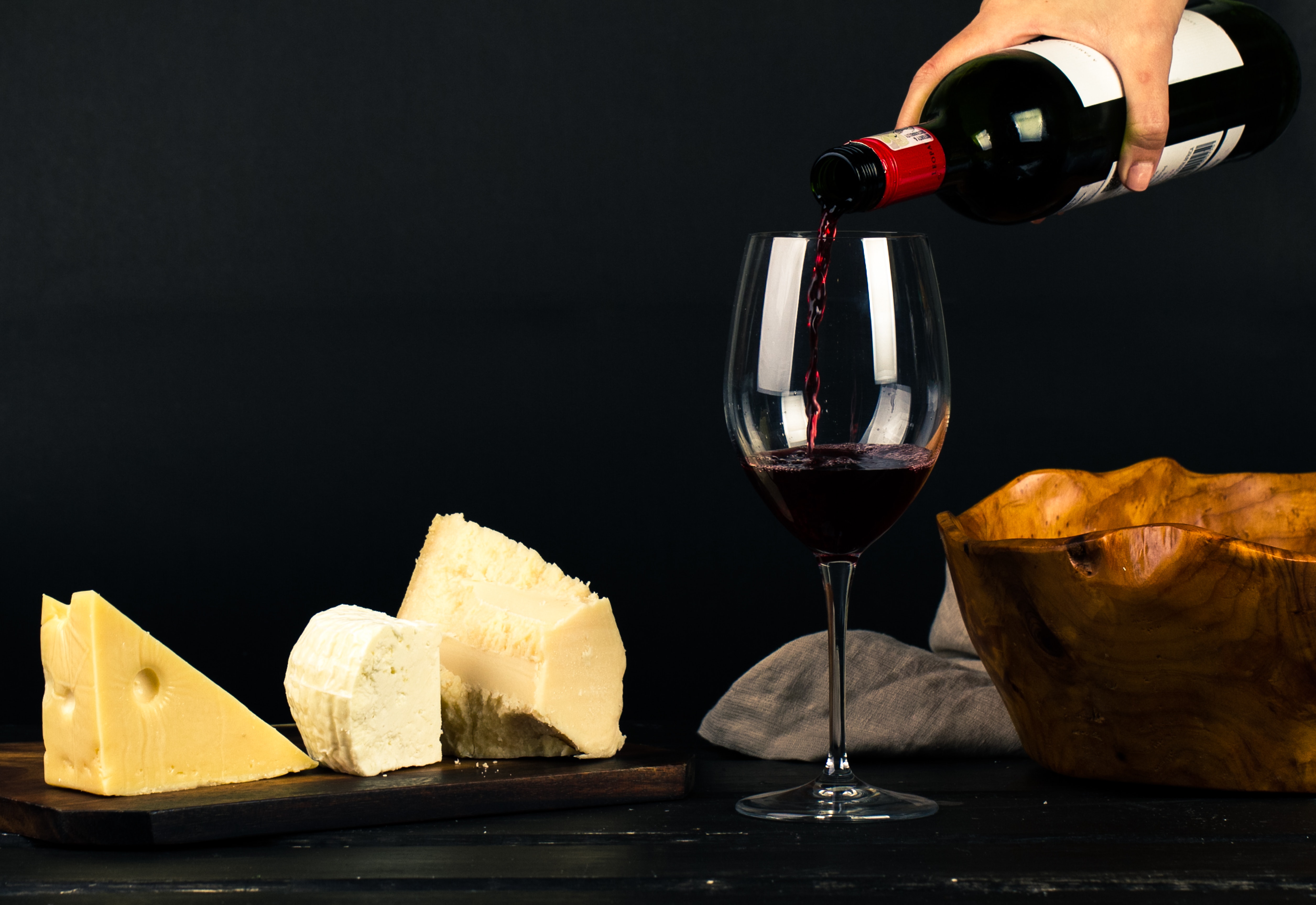 Foto von Wein und Käse vor schwarzem Hintergund